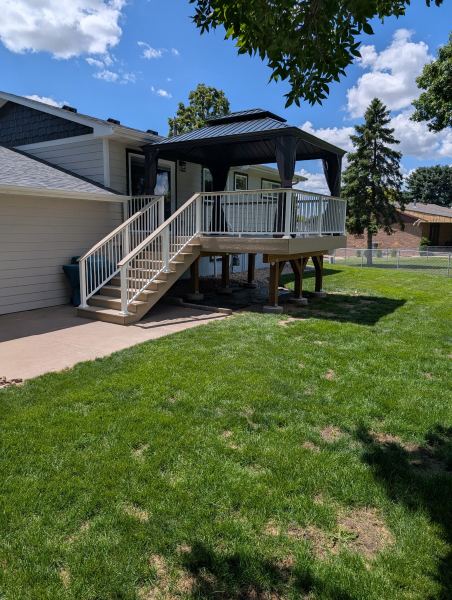 Raised backyard deck with white railings, stairs, and a gazebo