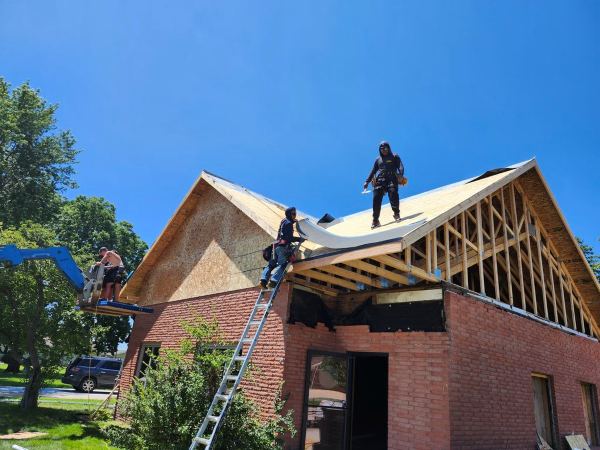 Crew installing roof sheathing on a second-story addition over a brick building