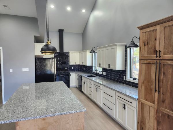 Remodeled kitchen with white cabinets, granite countertops, navy subway tile backsplash, and wood pantry cabinets